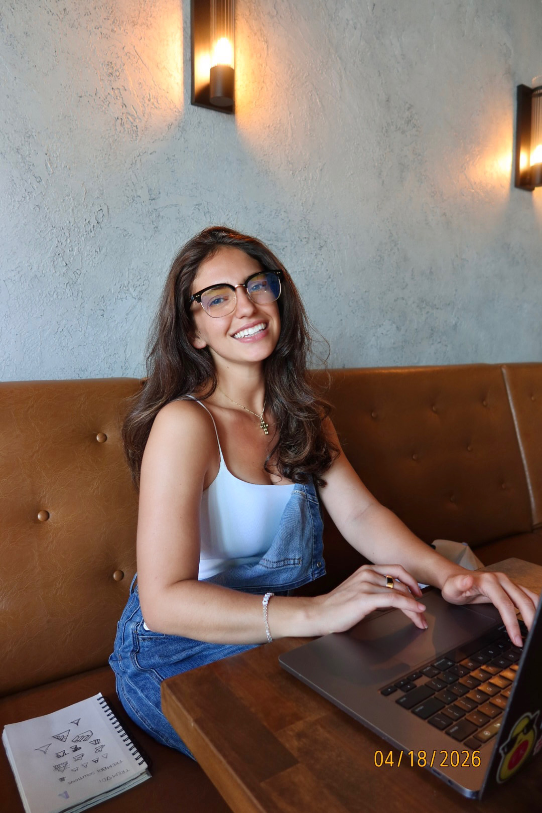 Isabel smiling while working on her laptop at a café