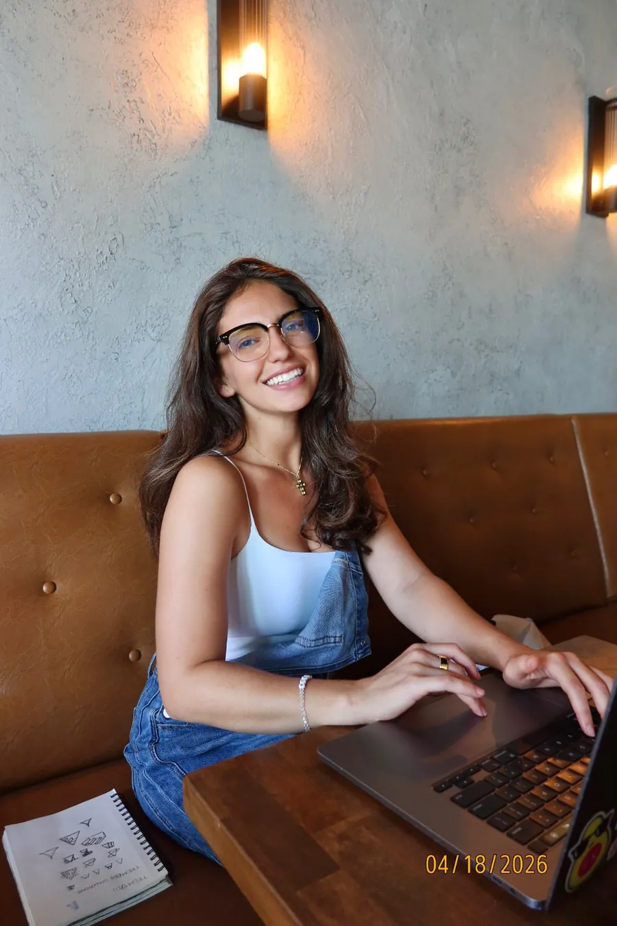 Isabel smiling while working on her laptop at a café